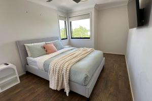 Sienna Rise - Walk to Westfield sleeps 6 North Lakes في البحيرات الشمالية: غرفة نوم بها سرير وبطانية عليه