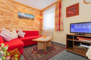 a living room with a red couch and a tv at Haus Traudi in Rauris