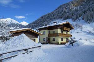 a house is covered in snow in the mountains at Haus Traudi in Rauris