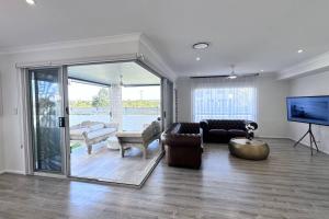 Lotus Grand Home in Mango Hill Sleeps 8 في البحيرات الشمالية: غرفة معيشة مع أريكة وتلفزيون