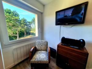 a room with a tv and a chair and a window at Le pré Colas- la maison néo bretonne in Pordic