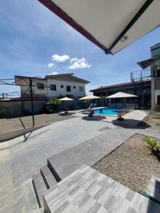 a patio with chairs and umbrellas and a pool at AOSMECPoolCamp Hotel in Lapu Lapu City