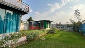 a small house in a yard next to a fence at Brasa farm in Gurgaon +2 photos