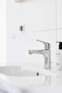 a bathroom sink with a faucet with water coming out at Duinhotel Tien Torens in Zoutelande