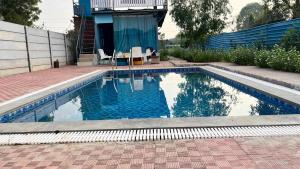 a swimming pool with two chairs and a house at Brasa farm in Gurgaon