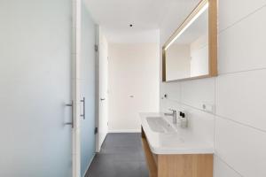 a white bathroom with a sink and a mirror at Duinhotel Tien Torens in Zoutelande