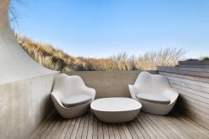 two white chairs and a table on a deck at Duinhotel Tien Torens in Zoutelande