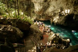 un grupo de personas de pie en un río en una cueva en Residencial La Fonte, en Santo Domingo