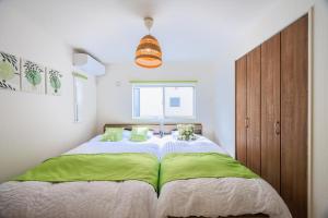 una camera da letto con un grande letto con lenzuola verdi e bianche di House FORMOSA中島 a Nagoya