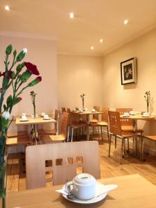 un restaurant avec des tables, des chaises et un vase de fleurs dans l'établissement Lord Jim Hotel London Kensington, à Londres