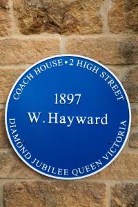 un panneau bleu sur un mur de briques dans l'établissement Historic Cotswold Chic Style for UK staycation, à Bourton-on-the-Water