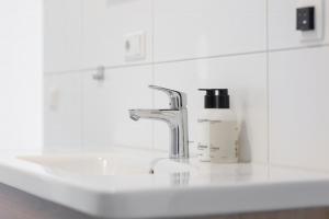a bathroom sink with a faucet and a bottle of soap at Duinhotel Tien Torens in Zoutelande
