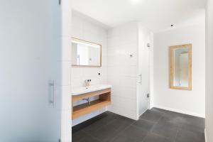 a white bathroom with a sink and a mirror at Duinhotel Tien Torens in Zoutelande