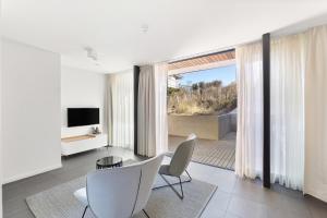 a living room with a table and chairs and a television at Duinhotel Tien Torens in Zoutelande