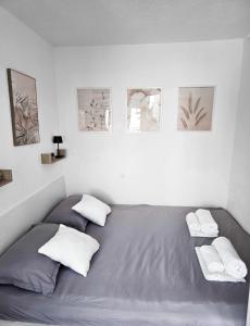 a bed in a white room with three pictures on the wall at Private bedroom with bathroom in Baška Voda
