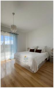 a bedroom with a bed with white sheets and a chandelier at Casa MarTeu in Pêra