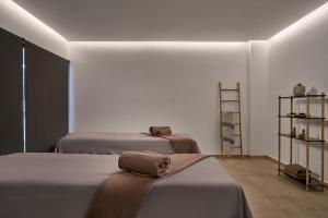 a bedroom with two beds with towels on them at Lindos Grand Resort & Spa - Adults Only in Lindos +83 photos