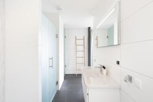 a white bathroom with two sinks and a mirror at Duinhotel Tien Torens in Zoutelande +37 photos