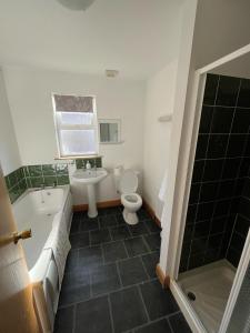 a bathroom with a toilet and a tub and a sink at Beach Haven Portstewart in Portstewart +3 photos