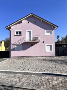 a pink house with a balcony on the side of it at La Nature by Leslodgespa - appartement confortable et ressourçant avec balcon, proche de Bâle et de l'aéroport in Hésingue +10 photos