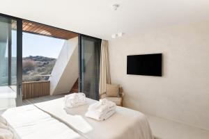 a bedroom with a bed with white sheets and a tv at Duinhotel Tien Torens in Zoutelande