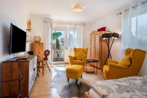 a room with a bed and a tv and chairs at Haus Grete in Langenargen