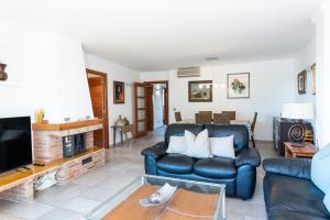 ein Wohnzimmer mit einem Ledersofa und einem TV in der Unterkunft Apartaments Marítim Torre Valentina in Sant Antoni de Calonge