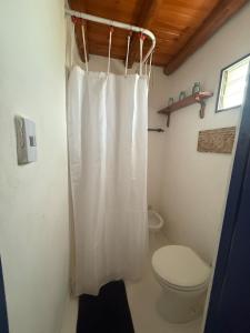 a bathroom with a toilet and a white shower curtain at Cabaña Chañar in Capilla del Monte +5 photos