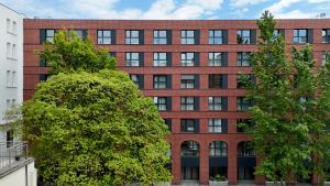 a red brick building with trees in front of it at Super-Apartamenty Plac Wolności 6 in Poznań
