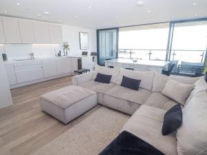 a living room with a couch and a kitchen at Seafront apartment with spectacular views in Porthcawl +35 photos