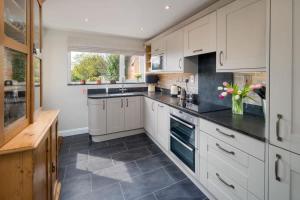 a kitchen with white cabinets and black counter tops at Lily Cottage in Gurnard