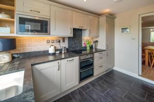 a kitchen with white cabinets and black counter tops at Lily Cottage in Gurnard