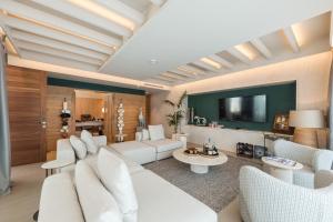 a living room with white furniture and a flat screen tv at Folie Marine Hotel & Beach Club in Jal