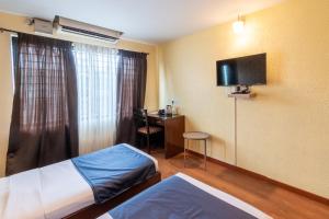 una stanza con due letti, una scrivania e una televisione di Chocolat house a Bangalore