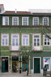 un edificio verde con ventanas blancas y un banco en Tea 4 Nine Guest House, en Braga
