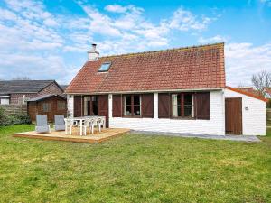 a white house with a table and chairs in the yard at Zeegalm Bungalows in Middelkerke