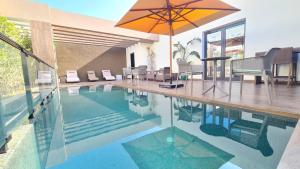 a swimming pool with an umbrella and a table and chairs at Camelia Ain Zaghouane in El Aouina Station