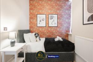 ein Schlafzimmer mit einem Bett und einer Ziegelwand in der Unterkunft 4BR Contractor House by Townhouse Stays, Short Lets & Serviced Accommodation in Colchester Free Parking, Garden & WiFi in Lexden