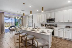 a kitchen with white cabinets and a large island with chairs at 295 Marcello Blvd in Kissimmee