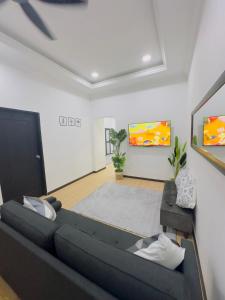 a living room with a black couch and a tv at 3Bedroom Landed Cozy Home Ipoh Netflix in Ipoh