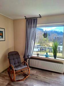 une chaise assise devant une grande fenêtre dans l'établissement Charmante, familienfreundliche Ferienwohnung im Herzen der Vulkaneifel, à Niederstadtfeld