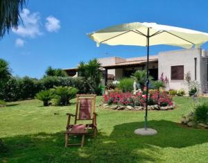 una silla y una sombrilla frente a una casa en Villa Egusa, en Favignana
