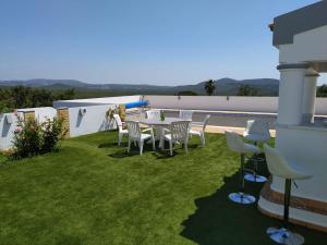 a patio with a table and chairs on the grass at Casa vista dos cerros in Loulé