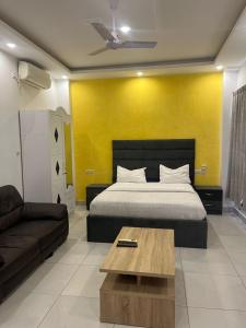 a bedroom with a bed and a couch and yellow wall at Les résidences Astou et Ndiaga in Dakar