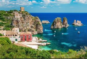 a beach with a red house in the water at La Dimora della Maestra in Vita