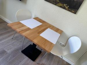 a wooden table with two white chairs next to a wall at Gemütliches Refugium am Bahnhof - Perfekt zum erkunden der Sächsischen Schweiz in Sebnitz