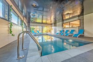 una piscina con sedie blu in una casa di La Villa des Légendes - Spa & Swimming Pool a Sizun