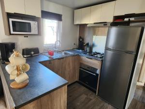 a kitchen with a stainless steel refrigerator and a sink at Mobil-home climatisé à Valras Plage dans le camping 4 étoiles les Sables du midi à 800m de la plage in Sérignan