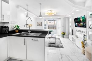 a kitchen with white cabinets and a sink at Spacious, Chic Townhouse with Parking & Garden in Birmingham