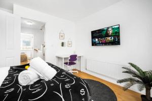 a bedroom with a bed with a tv on the wall at Spacious, Chic Townhouse with Parking & Garden in Birmingham